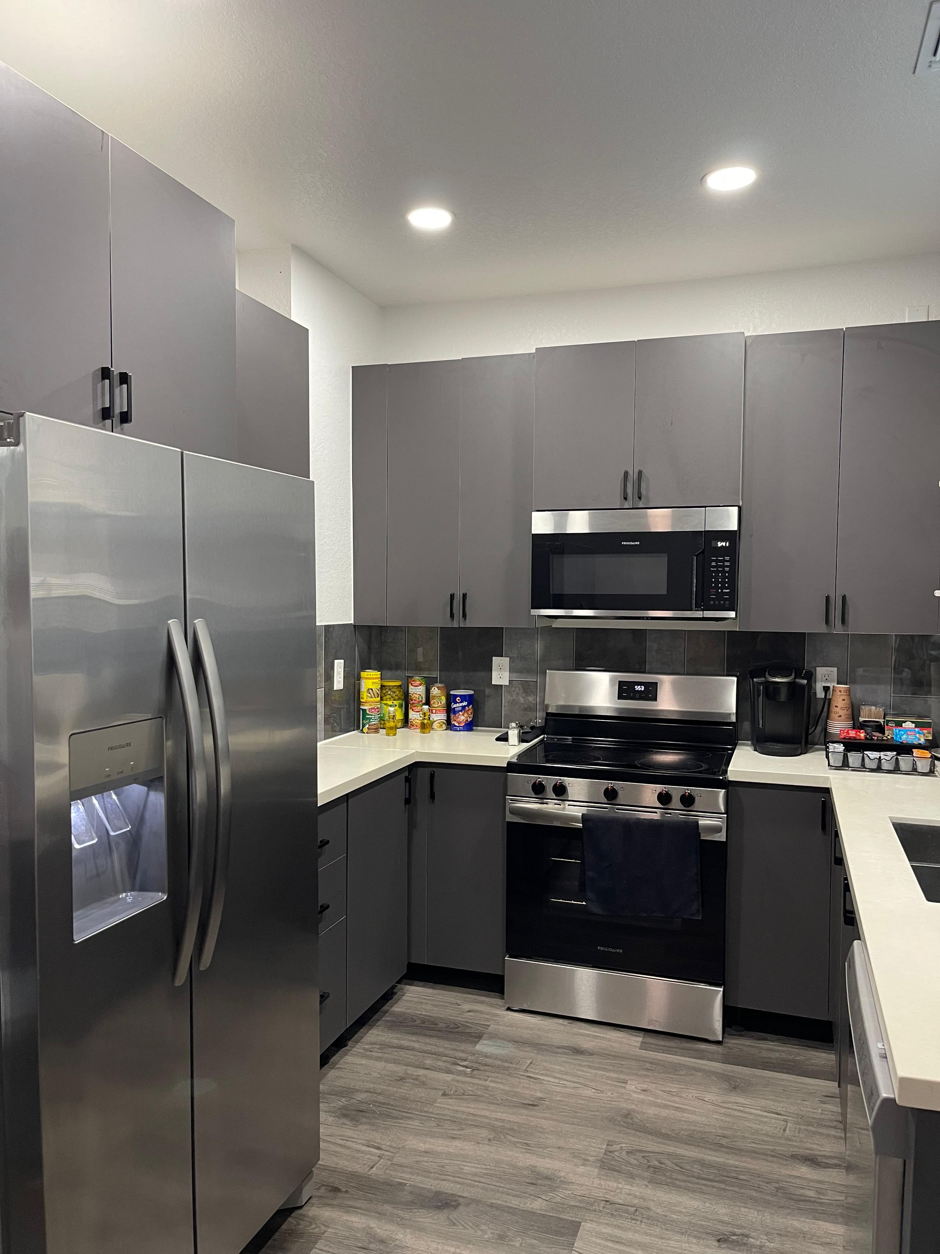 Compact apartment kitchen angle with refrigerator, range, microwave, and gray cabinets