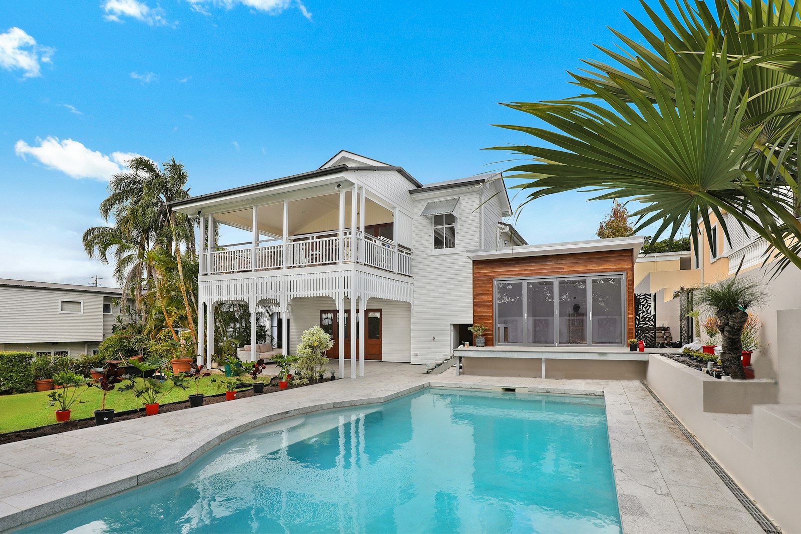 Bright residential rental property exterior with pool and palms